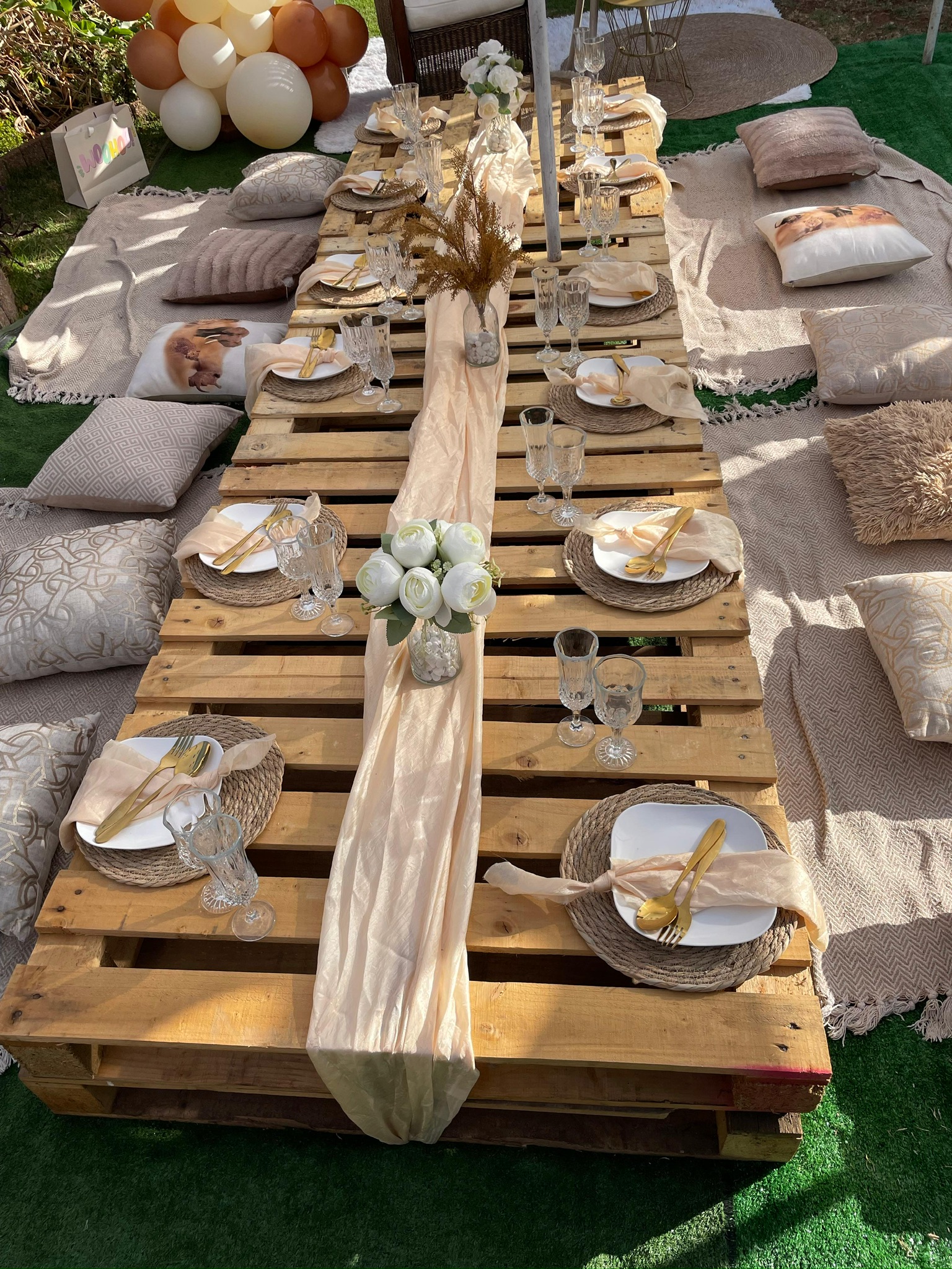 Boho outdoor picnic table setting with champagne glasses and flowers
